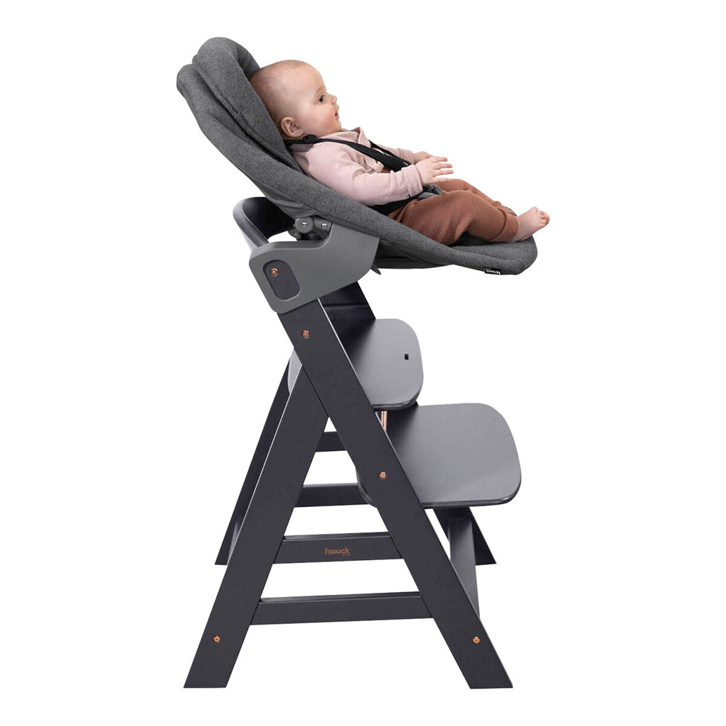 Barnestol Alpha+ med newborn-sett i bøk montert ved spisebord