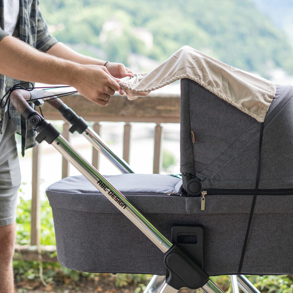 Bruksbilde med solseil til barnevogn med UV-beskyttelse 50+ beige i parken